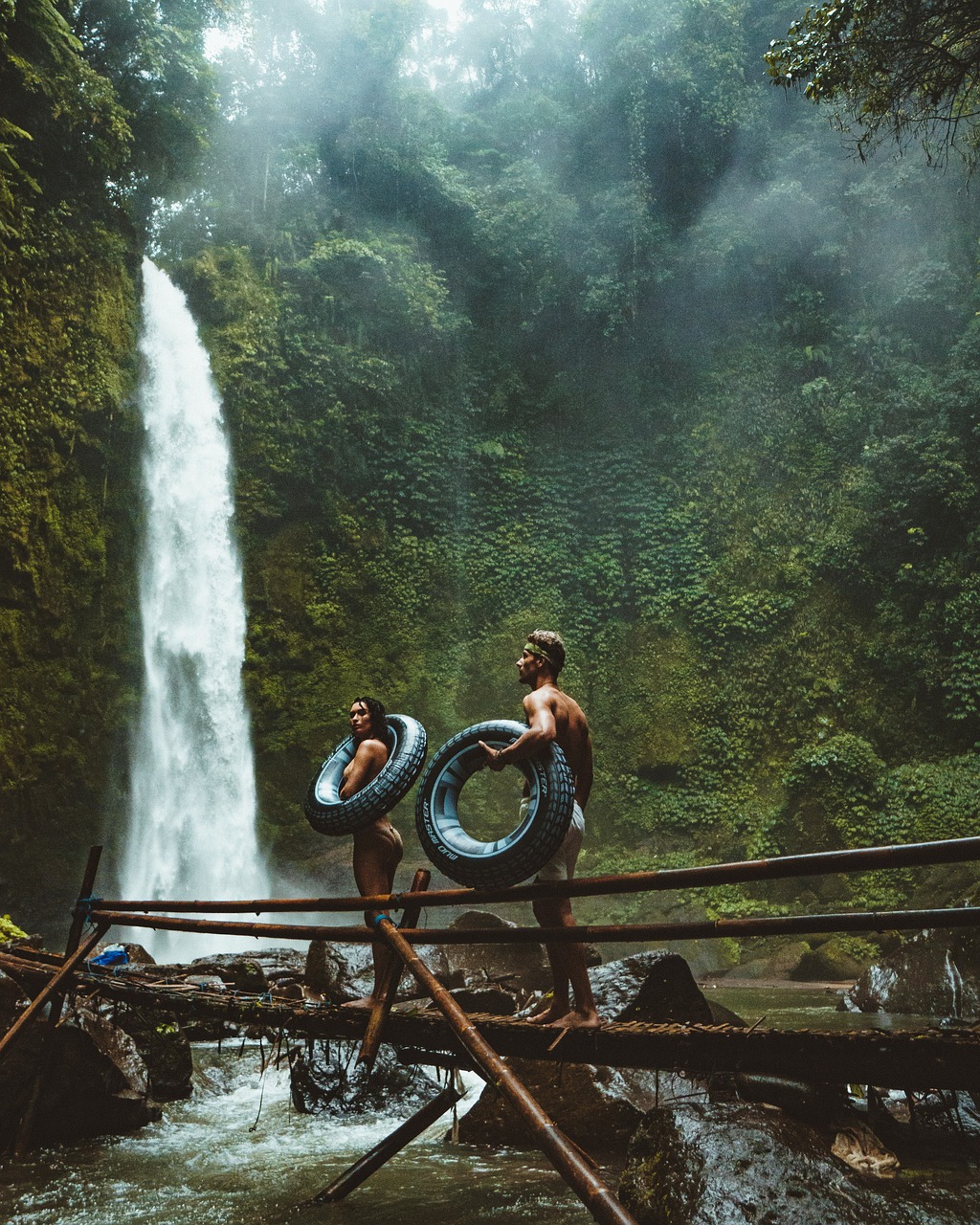 travel couple tubing waterfall river in paradise